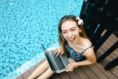 Portrait of top of happy female looking at camera with laptop onの写真素材
