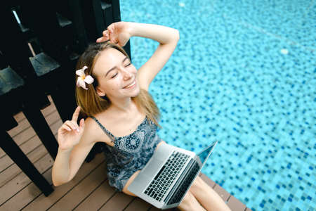 happy woman rest after hard work at swimming pool with laptop, dの写真素材