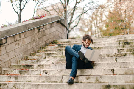 Mix blood businessman lying on steps with laptop.