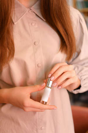 elegant sensual young woman holding perfume, golden tonesの写真素材