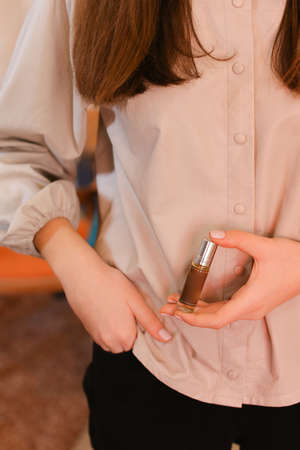 elegant sensual young woman holding perfume, golden tones