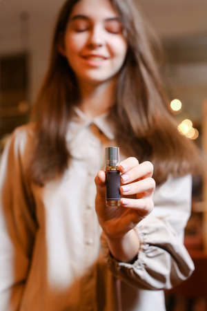 elegant sensual young woman holding perfume, golden tonesの写真素材