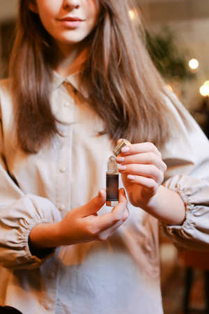 elegant sensual young woman holding perfume, golden tonesの写真素材