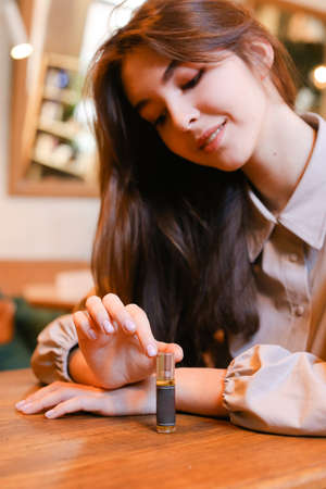 elegant sensual young woman holding perfume, golden tonesの写真素材