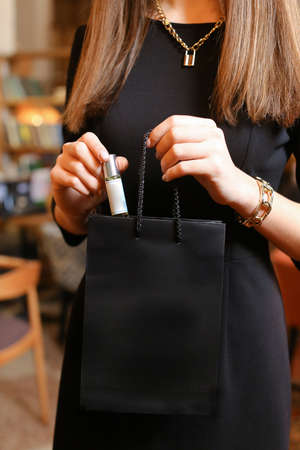 elegant sensual young woman holding perfume, golden tonesの写真素材