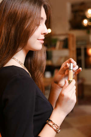 elegant sensual young woman holding perfume, golden tonesの写真素材