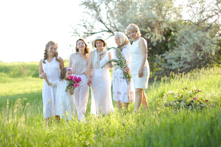 Happy granny standing with daughters and granddaughters, wearing white clothes outside.の写真素材