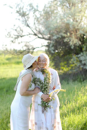 Portrait of daughter kissing old mother outside.の写真素材