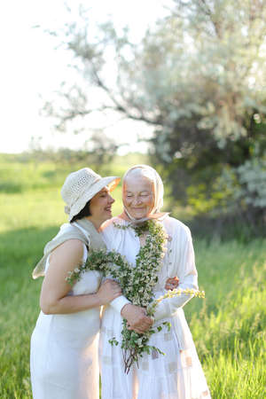 Portrait of happy daughter kissing old mother outside.の写真素材