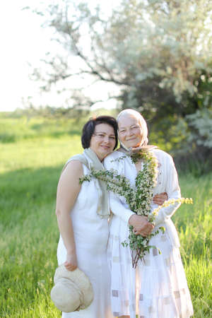 Portrait of happy grandmother with daughter in open air, wearing white dress.の写真素材