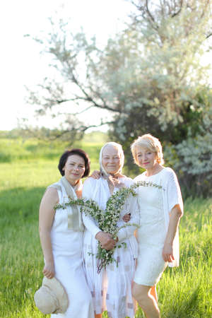 Portrait of happy grandmother with two daughters in open air, wearing white dress.の写真素材
