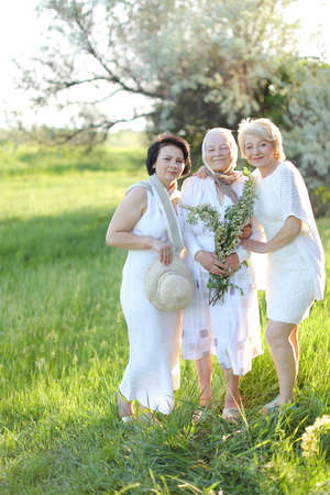 Two happy daughters standing with old mother outside and wearing white dresses.の写真素材