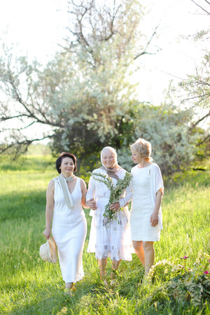 Two caucasian daughters standing with old mother outside and wearing white dresses.の写真素材