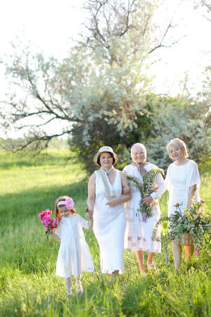 European grandmother in white dress with daughters and granddaughter outside.の写真素材