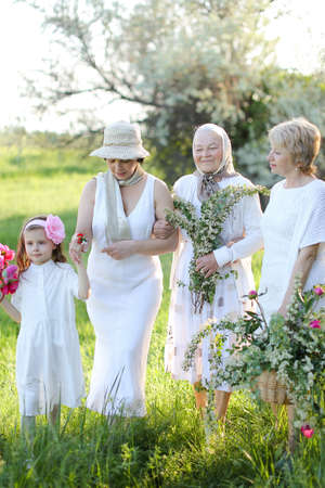 Nice grandmother in white dress with daughters and granddaughter outside.の写真素材