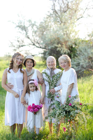 Caucasian grandmother in white dress with daughters and granddaughters outside.の写真素材
