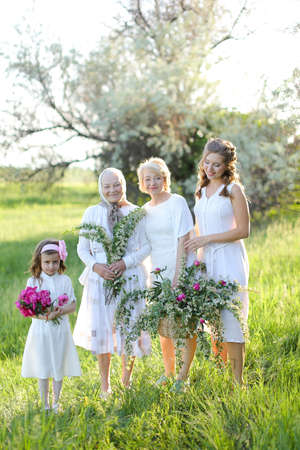 Caucasian granny in white dress with daughter and granddaughters outside.の写真素材