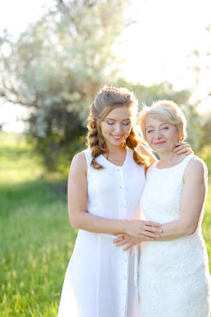 Portrait of american girl hugging mother outside and wearing white dress.の写真素材