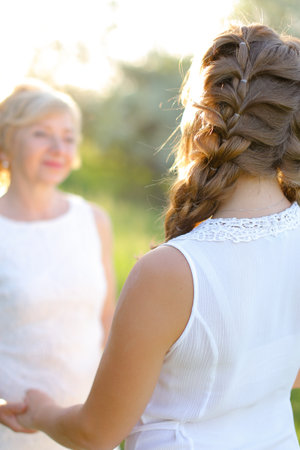 Focus on back view girl holding mother hands outside.の写真素材