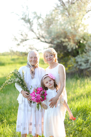 Caucasian grandmother in white dress with daughter and granddaughter outside.の写真素材