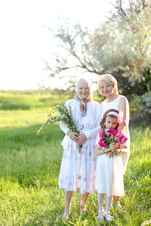 American grandmother in white dress with daughter and granddaughter outside.の写真素材