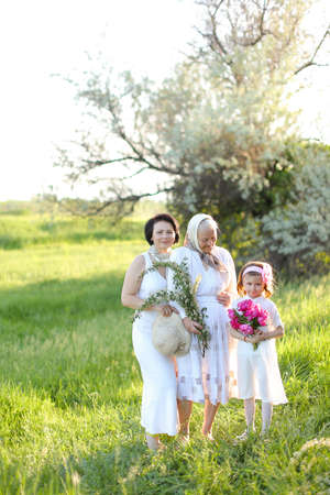 European old grandmother in white dress with daughter and granddaughter outside.の写真素材