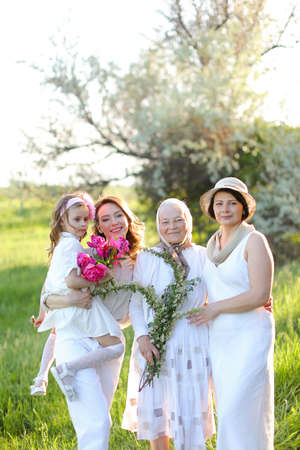 Caucasian grandmother in white dress with daughter and granddaughters outdoors.の写真素材