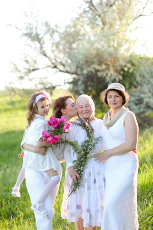 Young woman kissing granny and holding daughter outside.の写真素材