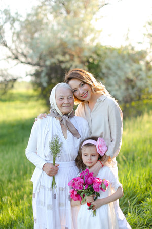 Young happy woman hugging granny and little daughter in park.の写真素材