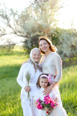 Young caucasian woman hugging granny and little daughter in park.の写真素材