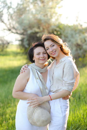 Young caucasian girl hugging mother in park and wearing white clothes.の写真素材