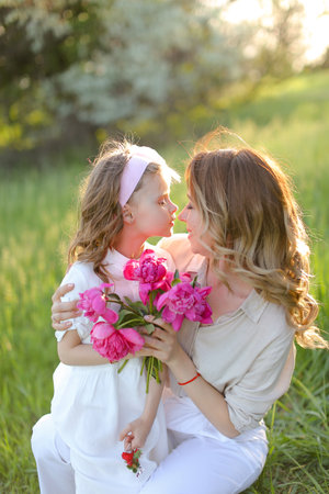 Portrait of happy young mother kissing little daughter on grass.の写真素材