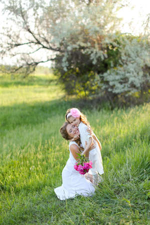 Young happy woman sitting with little daughter on grass.の写真素材