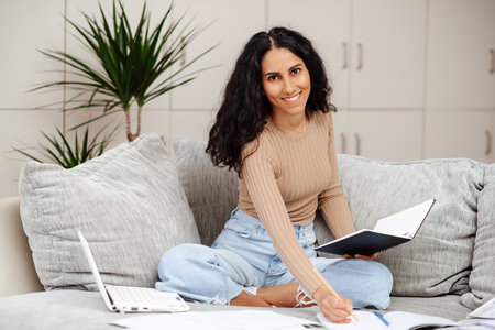 Happy Brunette Business Lady Using Laptop Smiling To Camera Posing Wearing Working Sitting At Workplace In Home Office. Successful Entrepreneurship And Career Concept. Smiling arab woman taking notesの写真素材