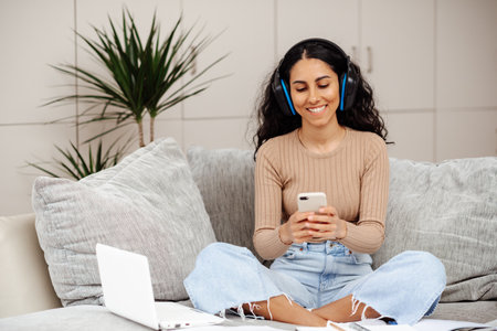 Arab girl teen enjoy learn MBA class study at home relaxed sit sofa work read text in social media, scroll laptop search app, watch wifi movie. Blogger girl smile happy life listen music multi task.の写真素材