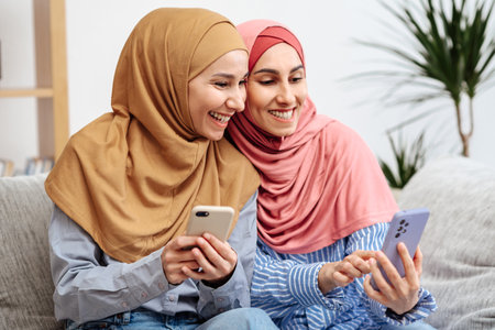 Muslim girlfriends checkout online order while sitting on sofaの写真素材