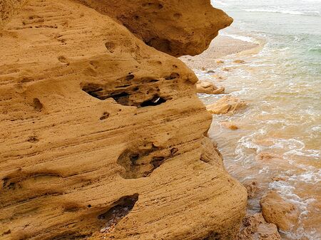 Closeup view on Brown shore rocks with winds and water signs, sea waves