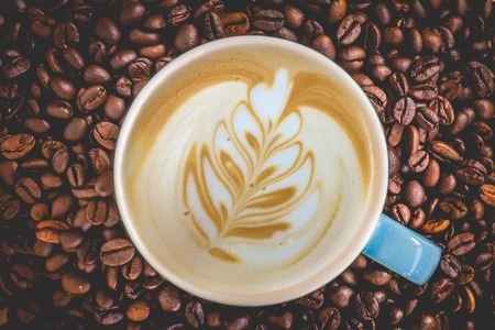 Latte art cup in coffee beans background.