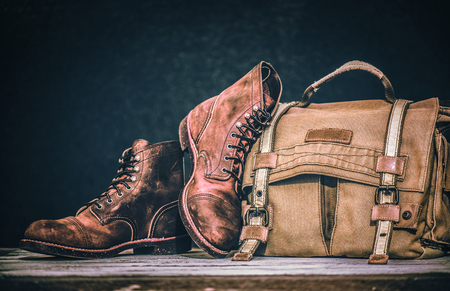 Men's boots and brown bag on wooden tableの写真素材