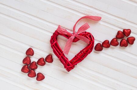 Red shiny hearts on a white wooden backgroundの写真素材