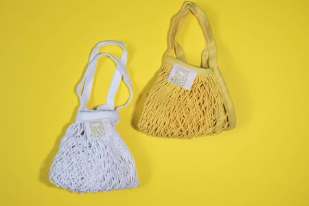 Reusable shopping bags white and yellow on yellow background. Zero waste concept. No plastic.
