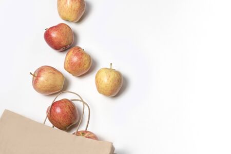 Paper bag of different health food on white background. Top view. Flat lay. beautiful juicy fresh apples, red-yellow apples in a paper bag, apples spill out of a brown paper bag, copy space, proper nutrition, diet, veganism, healthy nutrition, vitamins, Zero Waste, white backgroundの写真素材
