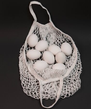 white chicken eggs in a string bag, on a black backgroundの写真素材