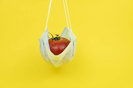 tomato in a medical mask on a yellow background.の写真素材