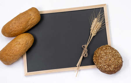 Different kinds of fresh bread on light background and black letter board top view flat lay