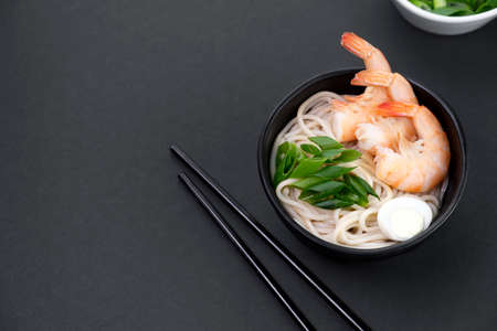 Healthy popular Asian street food. Close-up footage of traditional japanese ramen with shrimp, scallions and egg on black background.の写真素材