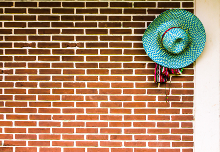 Farmer's hat hung beside an old orange brick wall.の写真素材