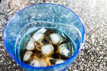 Brown drink ice cubes in a glass of four blue. Refreshing drinkの写真素材