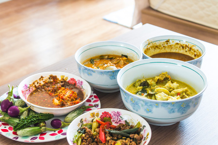 The poor eat a cup of spicy chili paste with vegetables and wild curry on a wooden table.の写真素材