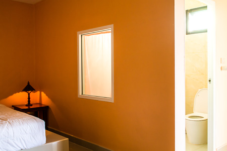 The bedroom has a lamp next to the bed. Ensuite bathroom And with white windows.の写真素材